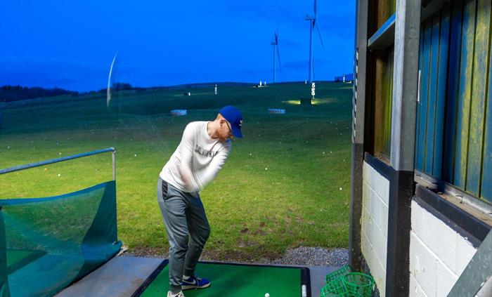 Golfers hone their skills at the driving range.